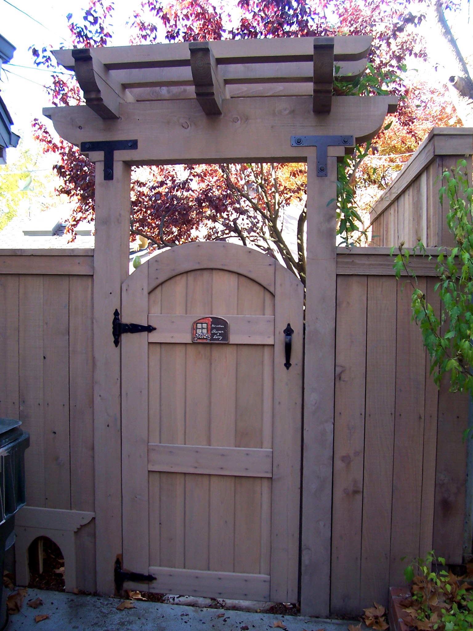 Custom wood garden gate and arbor with decorative metal hardware