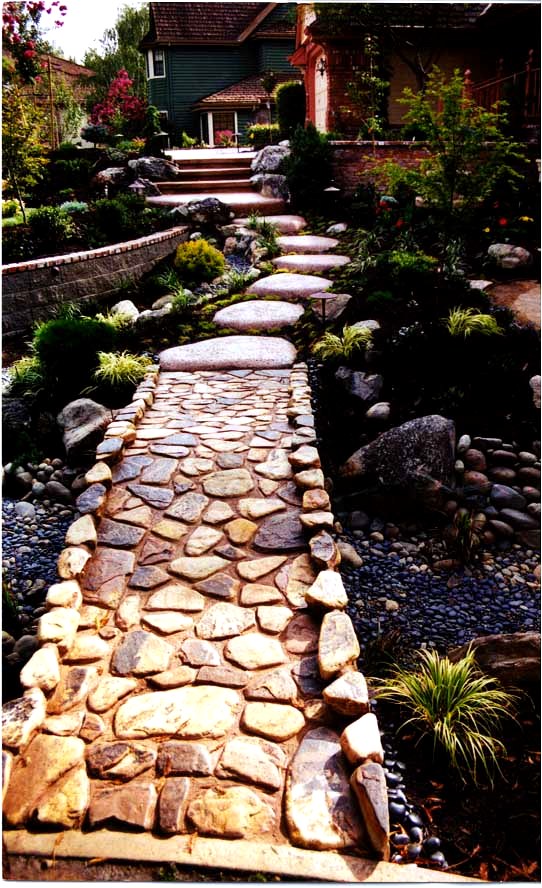 Natural stone garden path surrounded by layered planting and landscape rock